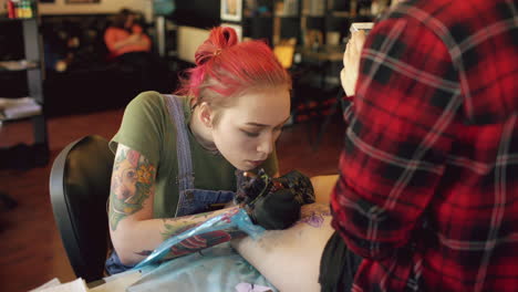 tattoo artist working on client's leg