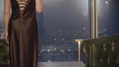 woman in a satin dress with champagne, night city view