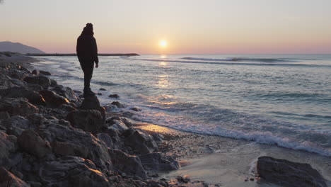 Der-Mann-Nutzt-Sein-Telefon,-Um-Während-Des-Atemberaubenden-Sonnenaufgangs-Einen-Wunderschönen-Blick-Auf-Das-Meer-Einzufangen,-Während-Sich-Die-Sonne-Auf-Der-Oberfläche-Spiegelt