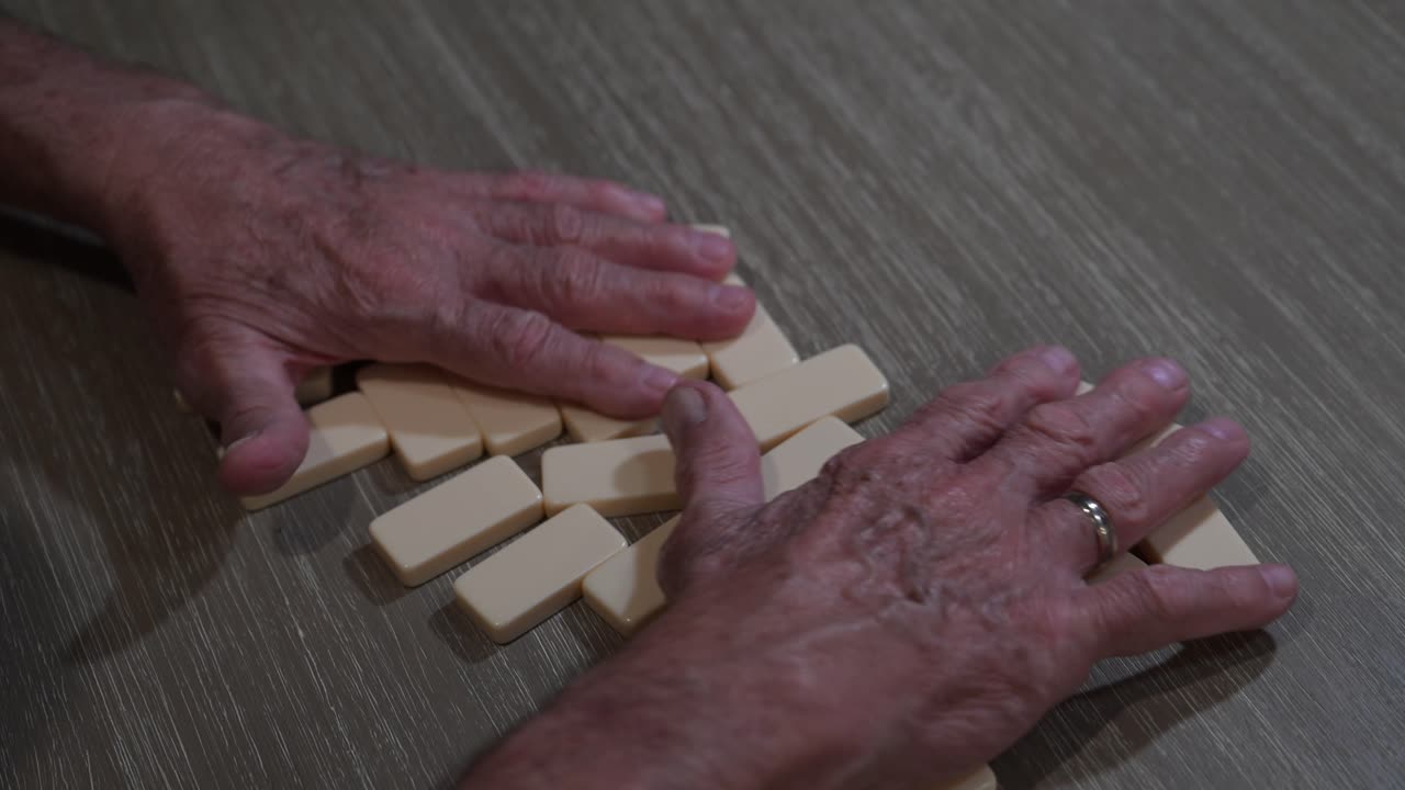 elderly hands shuffle dominoes during a big game with friends