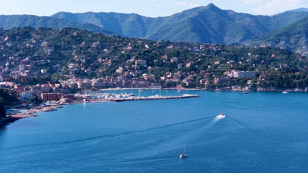 Ripresa dall'alto di una barca che naviga in acque calme del Mediterraneo vicino a un porto.