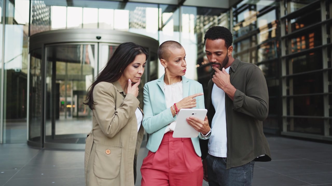 Diverse Business Team Discussing Project on Tablet Outside Office Building