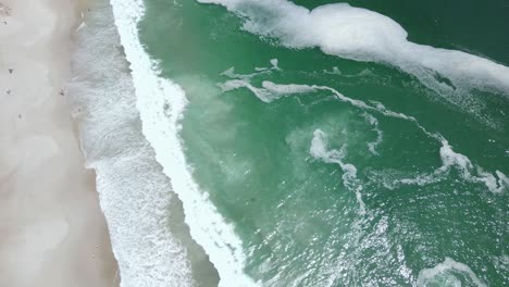 espuma blanca flotando en el océano de agua verde del clan y la costa de arena marrón