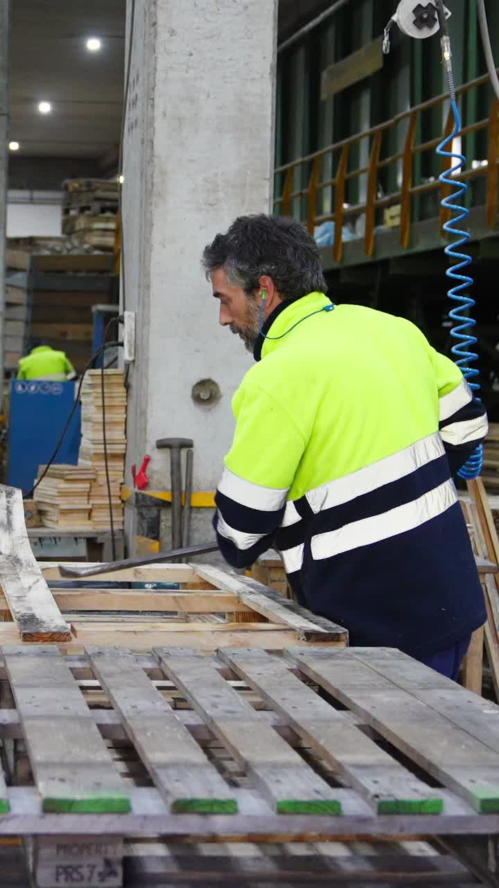 Un trabajador montando palés de madera en una fábrica