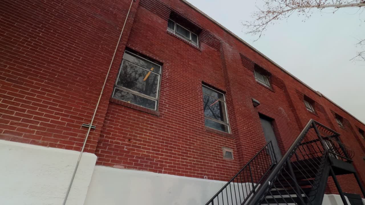 Barrido lento de izquierda a derecha mostrando la fachada de un edificio de ladrillo y una escalera metálica exterior