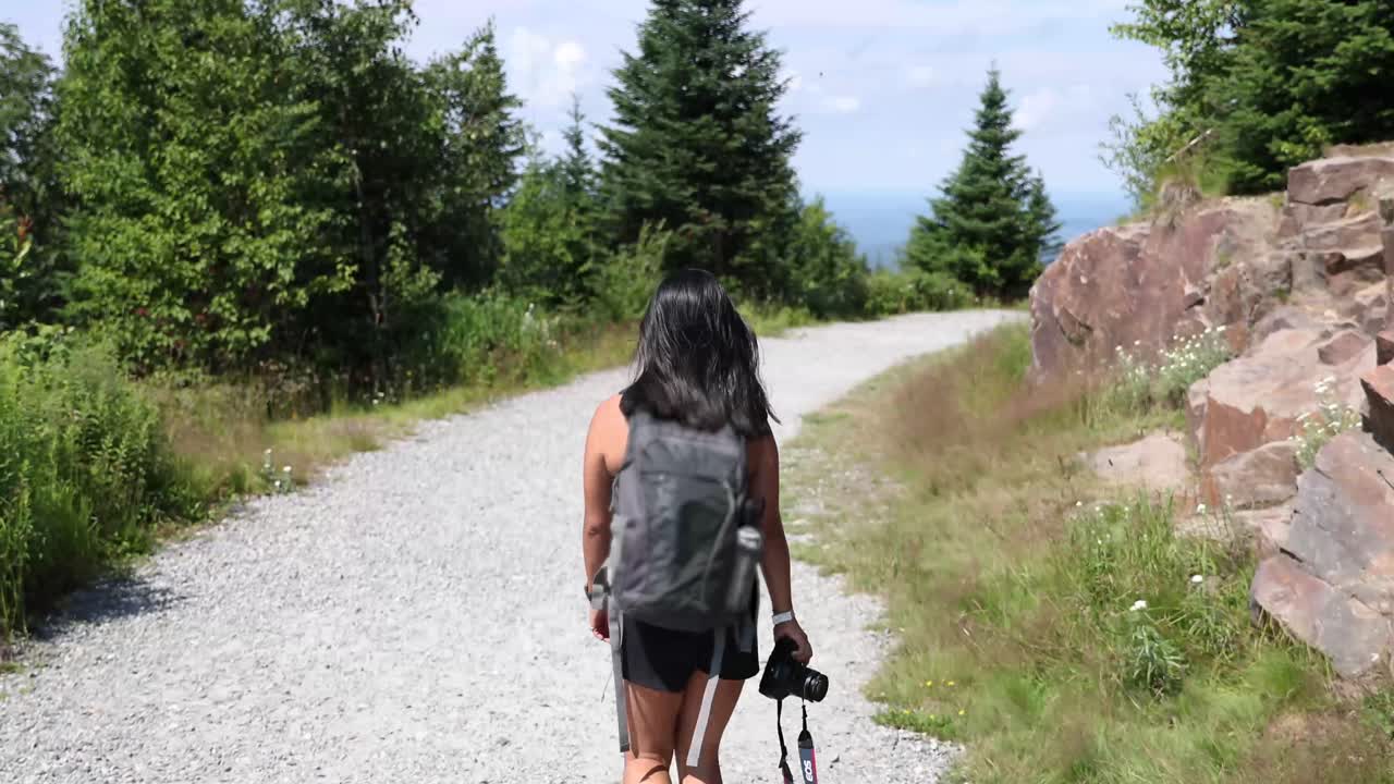 excursionista femenina caminando por un sendero en la cima de una montaña soleada en tremblant en verano
