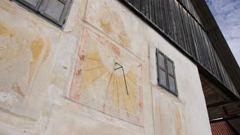 Sonnenuhr-Fresko-Gemalt-Auf-Altem-Bauernhaus-Im-Dorf-In-Slowenien,-Dolly-Aufnahme