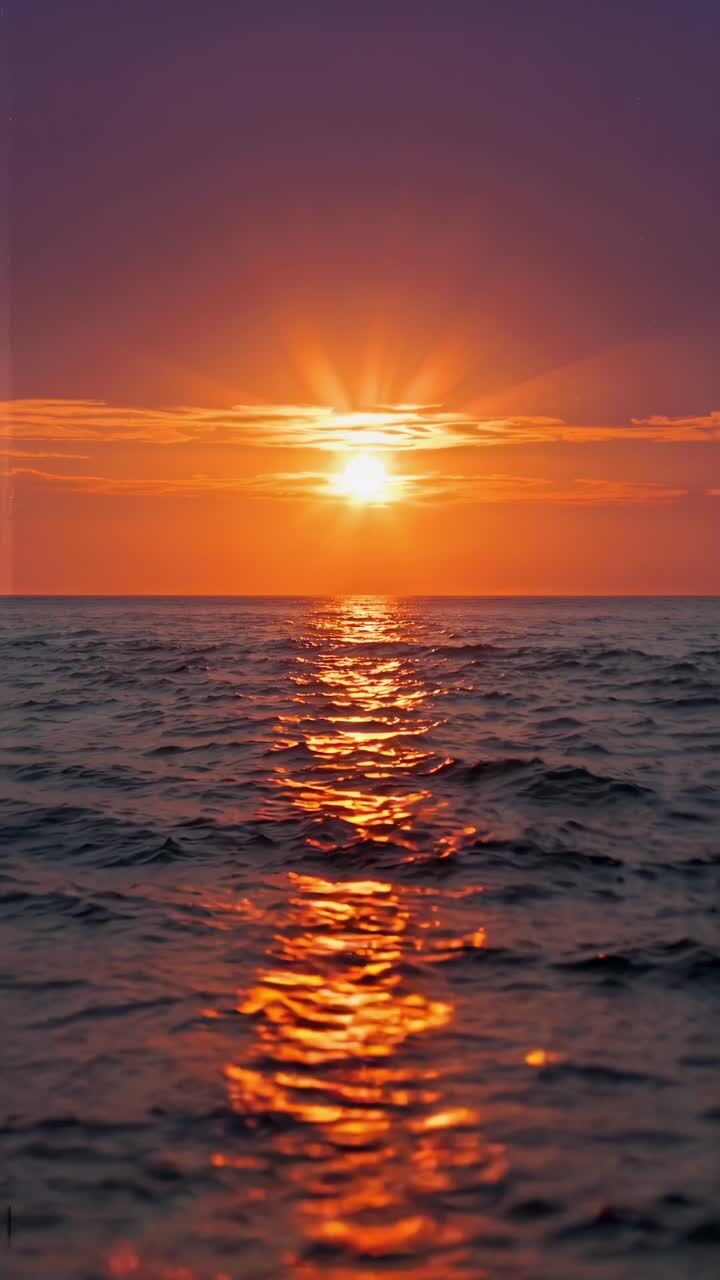 A serene sunset over the ocean, captured from a low angle. The vibrant colors and gentle waves