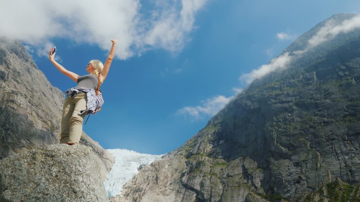 Una giovane donna di successo si fotografa contro lo sfondo di montagne e un ghiacciaio in Norvegia