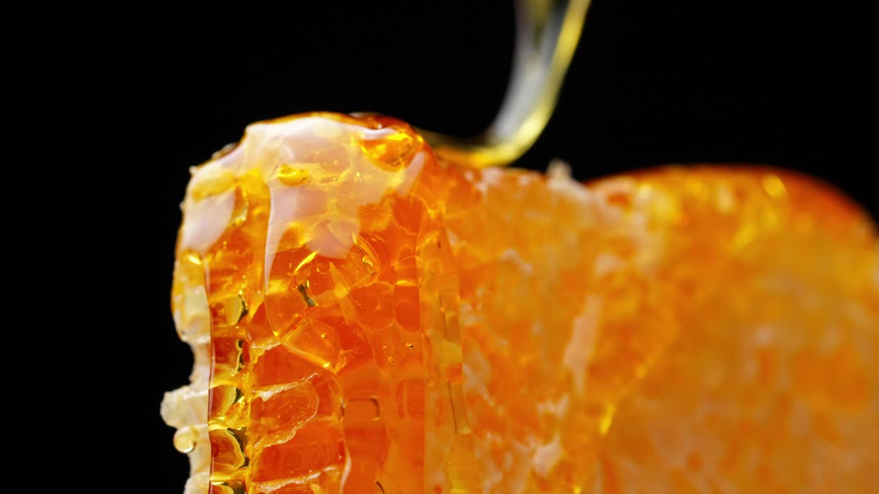 Macro ravvicinata di miele che si espande attraverso le celle a nido d'ape con colori intensi e lucentezza, deliziosa luce ambrata dorata