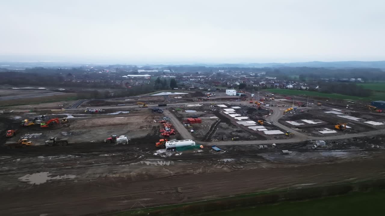 Arcing shot revealing housing plots surrounded by heavy machinery on a site