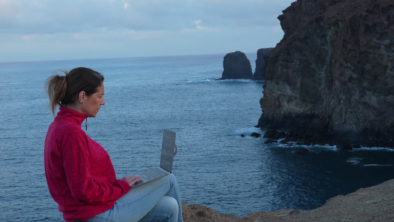 Freelancer working with laptop on a cliff in Gran canaria, canary islands, spain. Slow motion video