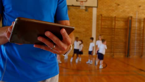 Entrenador-De-Baloncesto-Usando-Tableta-Digital-En-La-Cancha-De-Baloncesto-De-La-Escuela-4k