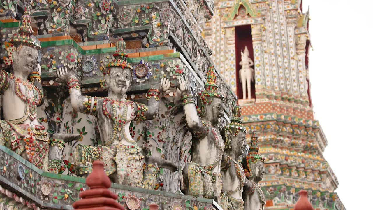 A video capturing the detailed architecture of Wat Arun in Bangkok, featuring ornate sculptures and vibrant colors under natural daylight