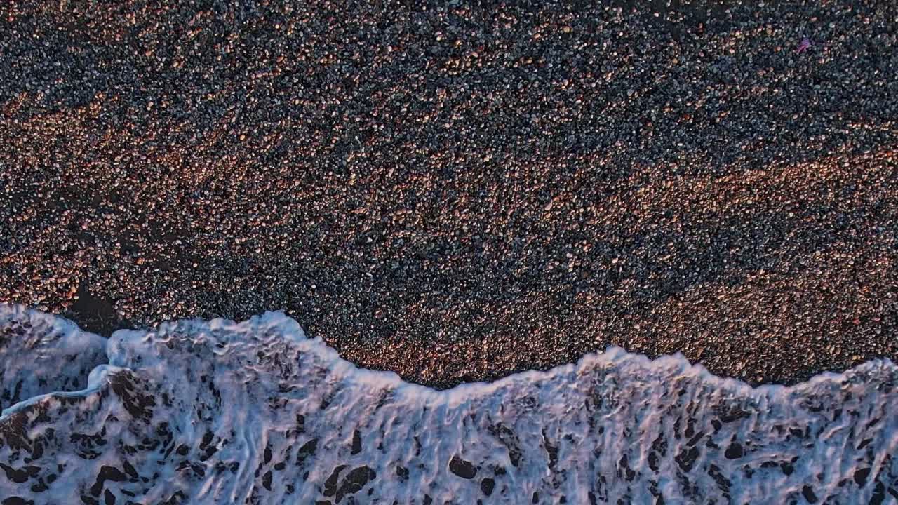 Waves crashing on the pebbled beach in Rhodes, Greece during sunset