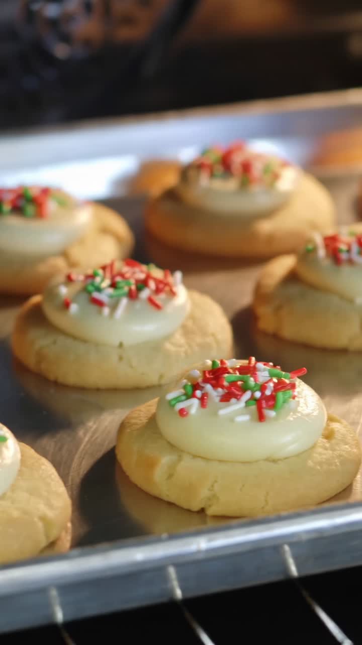 Vertical video: Placing tray with iced sugar cookies and sprinkles in oven for baking until golden
