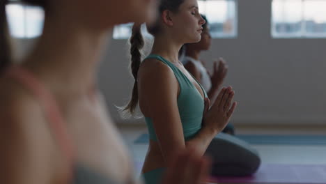 beautiful caucasian woman in yoga class practicing mindfulness exercise with meditation group enjoying healthy lifestyle fitness studio training at sunrise