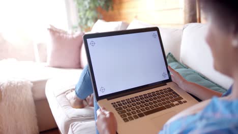 Happy-african-american-woman-using-laptop-with-copy-space-on-screen-in-living-room,-in-slow-motion