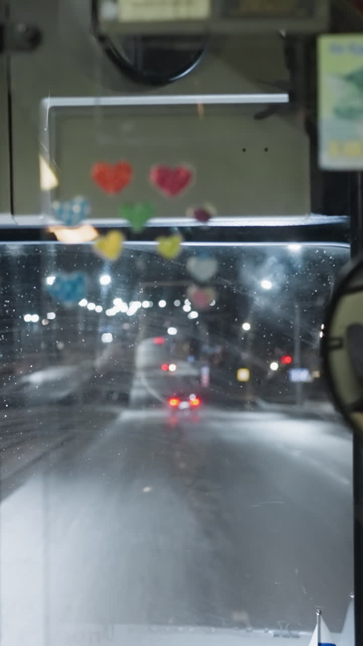 밤에 고속도로에서 운전하는 자동차의 내부 시각, 조명된 대시보드, 뒷면 거울 반사, 바의 도시 조명, 움직이는 다른 자동차를 보여줍니다.