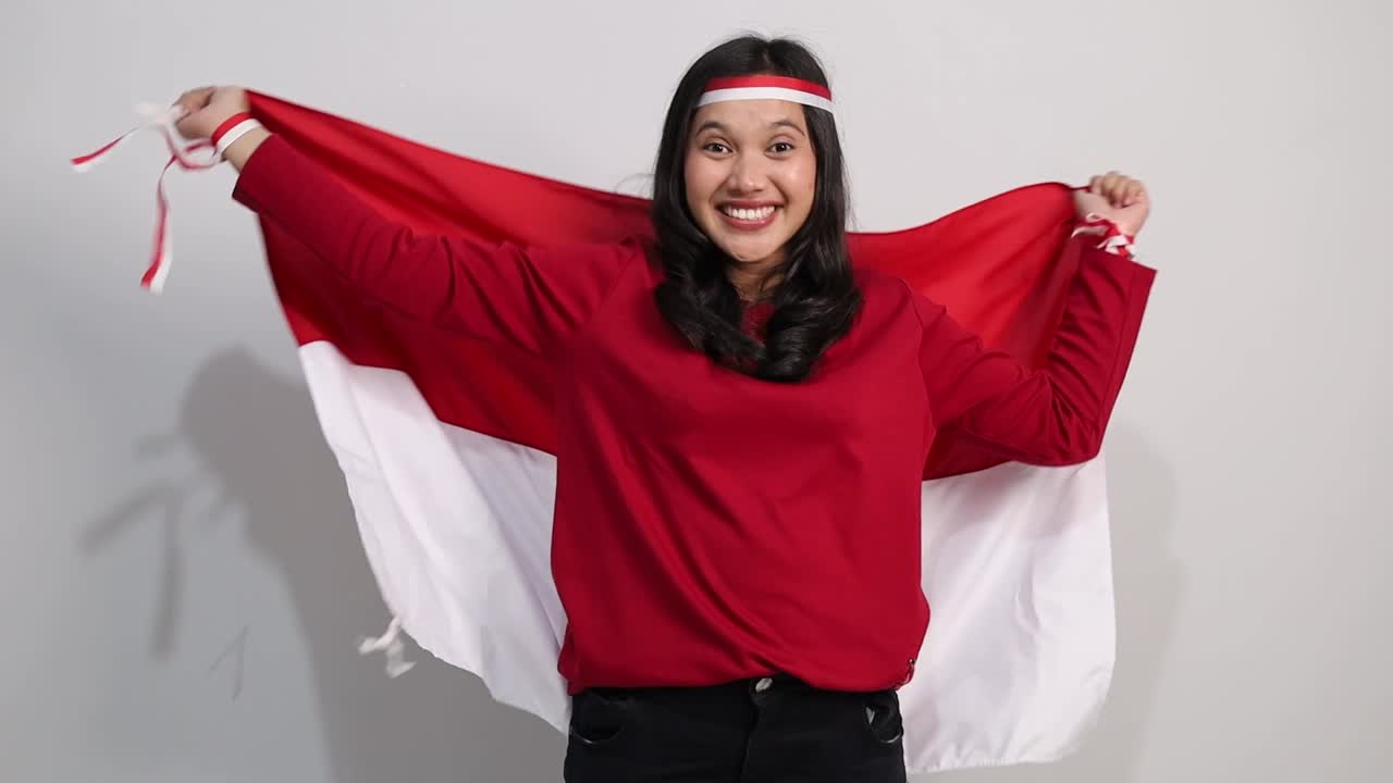 Young Indonesian woman celebrate Indonesian independence day on 17 August by holding the Indonesian flag isolated over white background