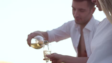 un bel homme versant du champagne dans des verres à vin. un couple d'amour se détendant à l'extérieur