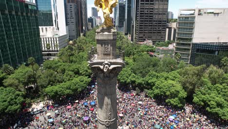 Toma-Ascendente-De-Un-Drone-De-Un-Desfile-Masivo-Del-Orgullo-Gay-En-La-Ciudad-De-México-Con-El-Monumento-A-La-Independencia-En-Primer-Plano