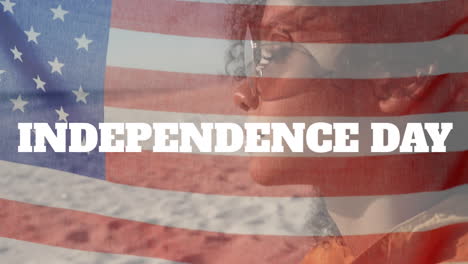 animation of independence day text, flag of american, close up of beautiful biracial woman at beach