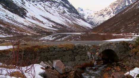 An-old-stone-bridge-near-a-reflecting-fjord-in-Norway