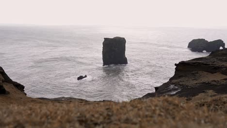 rocky cliff washed by foamy sea in overcast weather