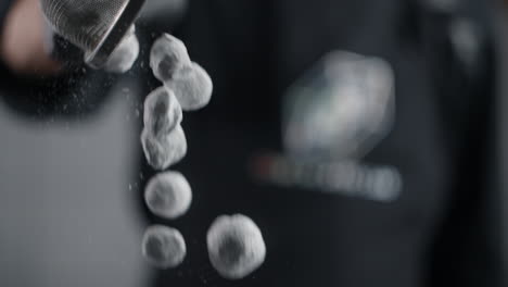 chef sifting powdered sugar over small balls