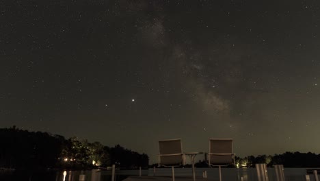 Noche-Estrellada-Sobre-Un-Lago-Con-Dos-Sillas-En-Un-Muelle,-Timelapse