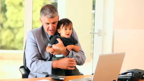 Man-in-office-coping-with-baby-and-laptop