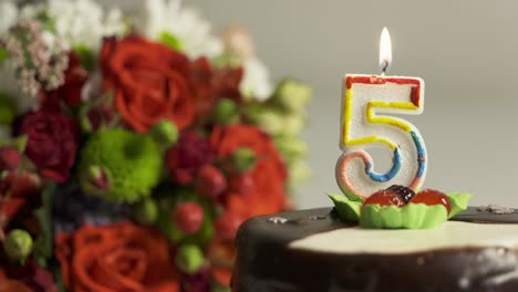 dolly: arreglo de flores y pastel de cumpleaños con vela encendida número 5