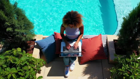 woman working on laptop by the pool