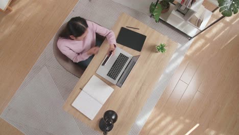vista superior zoom out toma de una mujer asiática molesta perdiendo un juego en el teléfono inteligente mientras estaba sentado en la madera en casa