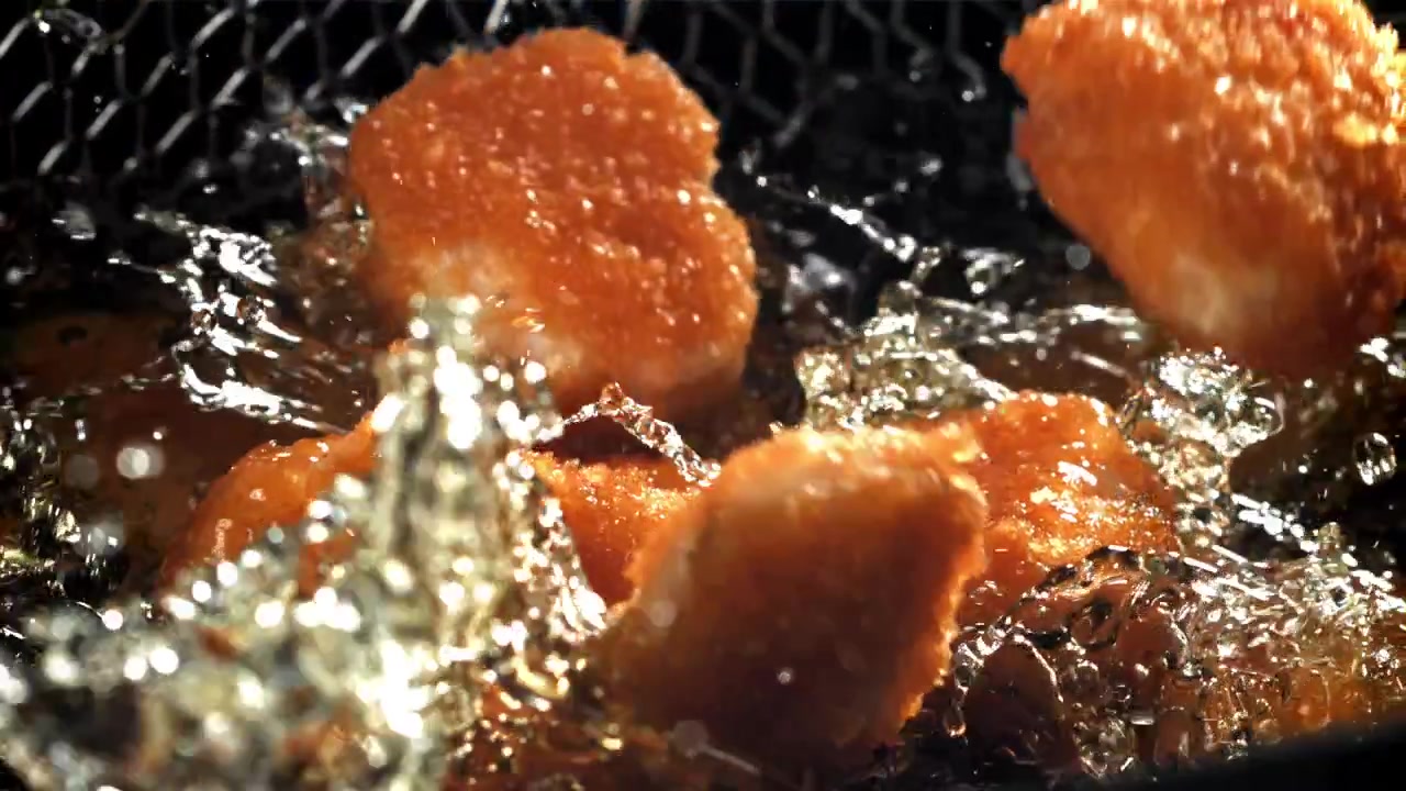 熱い揚げ油にチキンナゲットが落ちるスローモーション
