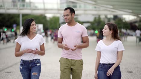 smiling relaxed friends walking on street and talking