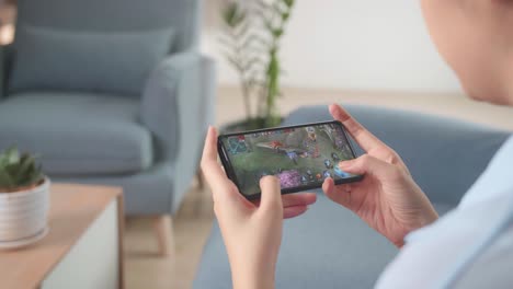 hands female playing game on smartphone at home living room, video in 4k