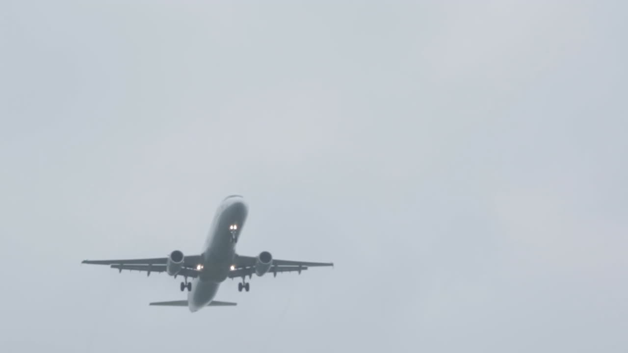 Plane flying over camera. Wide to close shot. Cloudy day with fog