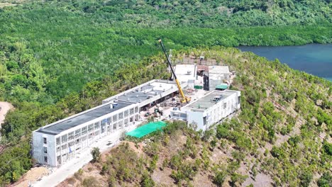 tower crane on the construction site over a tropical mountain of busuanga bay in palawan, philippines. aerial drone shot