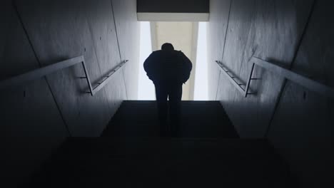 male silhouette walking up on staircase in bright light background,