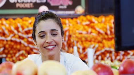 female staff arranging apples in organic section