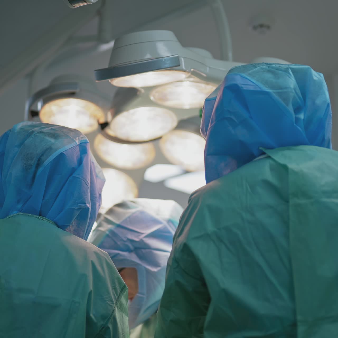 Teamwork of doctors in protective clothing. Group of medical workers in safety uniform operating patient in clinic. Rear view. Coronavirus concept