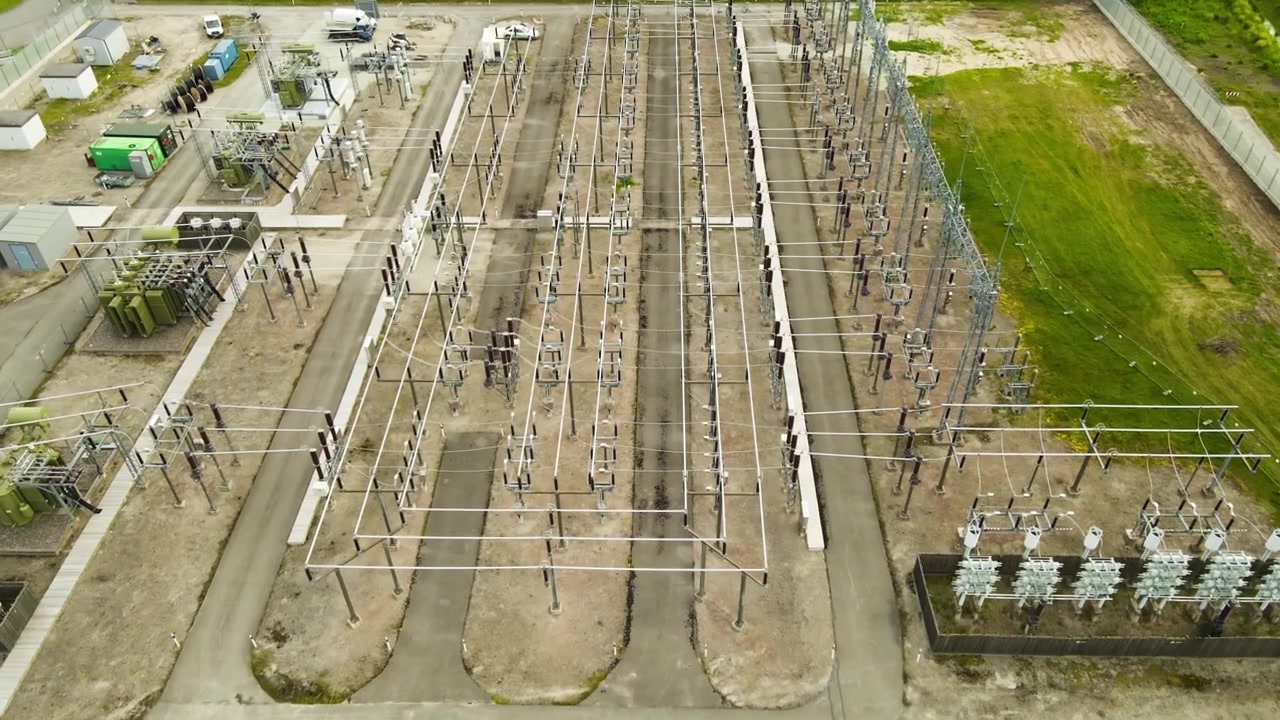 Luftaufnahme eines großen Umspannwerks mit komplexen Stromleitungen, Isolatoren und Transformatoren, die die Infrastruktur für Stromerzeugung und -verteilung hervorhebt