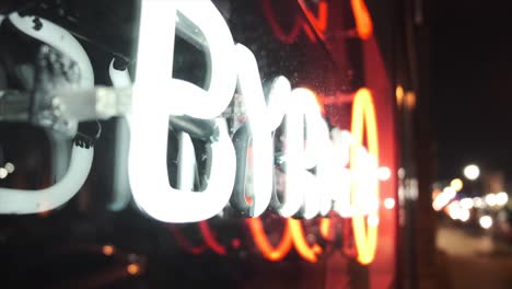 close up defocused pedestal shot of a neon sign at night, side view