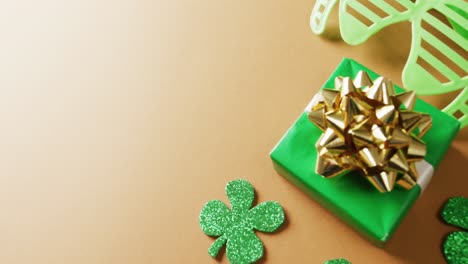 Video-of-saint-patricks-day-green-shamrock,-present-and-glasses-with-copy-space-on-orange-background