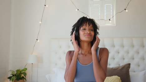 african american woman enjoying music with headphones, dancing joyfully at home