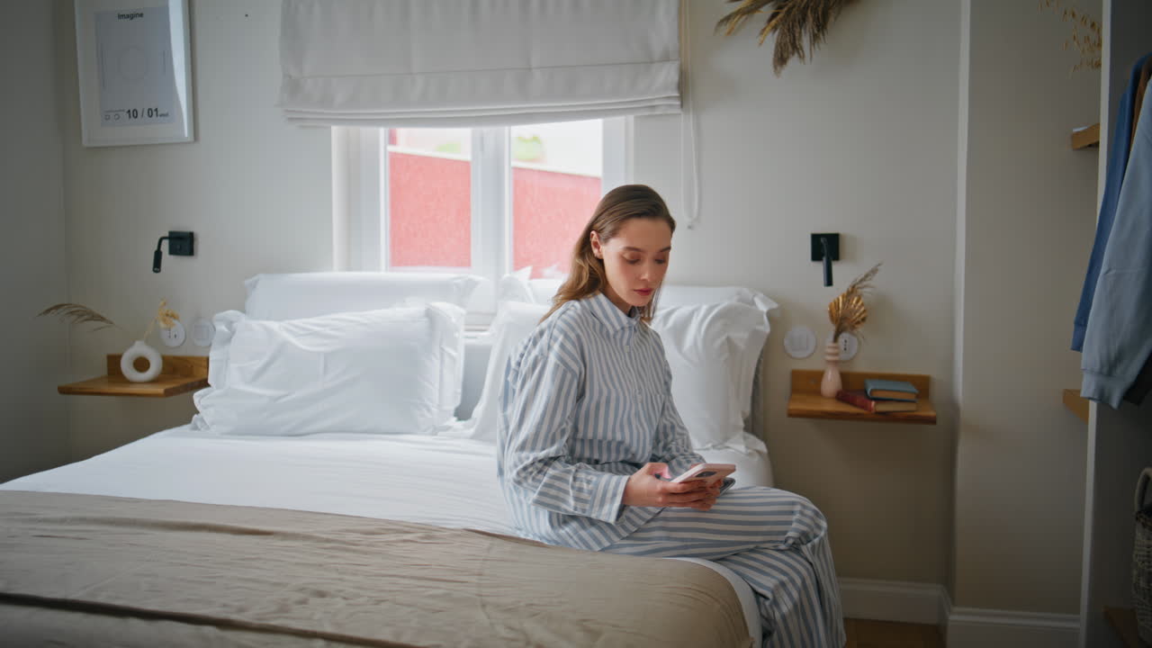 Lady using smartphone bed after wake up. Young woman reading cellphone message