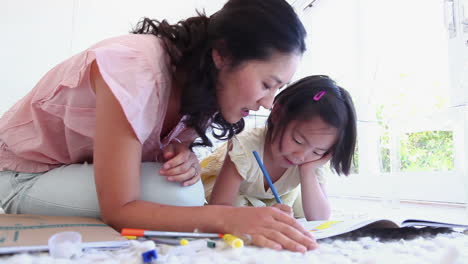 woman watches a girl as she colours