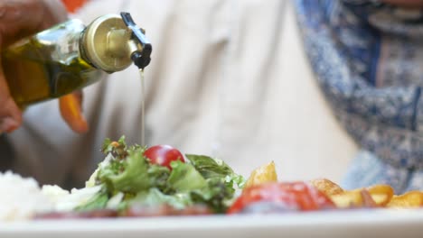 woman pouring olive oil on salad